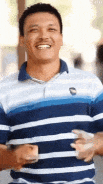 a man in a blue and white striped shirt is smiling and holding money