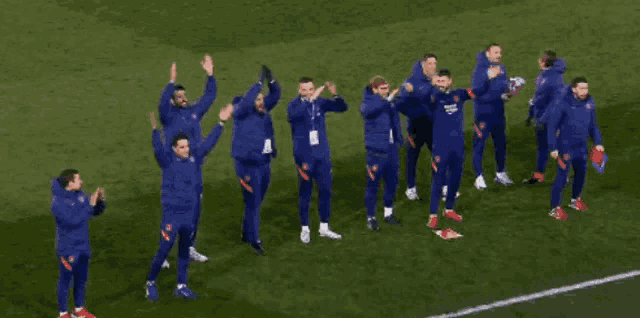 a group of soccer players are standing on the field with their arms in the air
