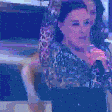 a woman singing into a microphone in a blue and purple background