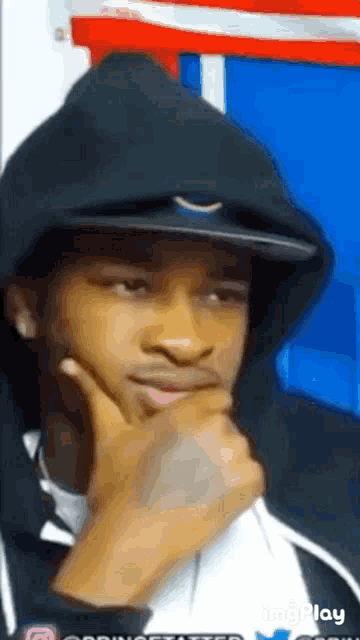 a man wearing a hoodie and a hat is thinking with his hand on his chin