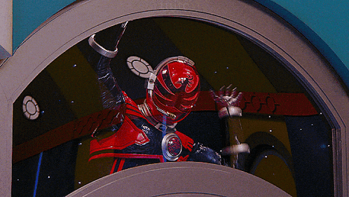 a man in a red and black costume is waving his hand