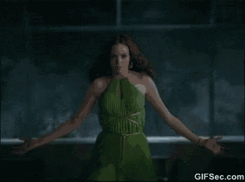 a woman in a green dress is standing in front of a window with her arms outstretched