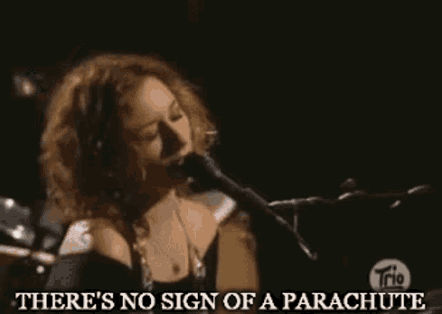 a woman singing into a microphone with the words there 's no sign of a parachute above her