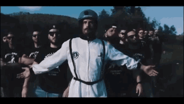 a man with a beard wearing a helmet is standing in front of a group of people .