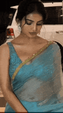 a woman in a blue blouse is standing in front of a car