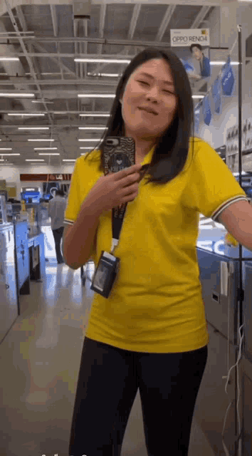 a woman in a yellow shirt is taking a selfie in a store