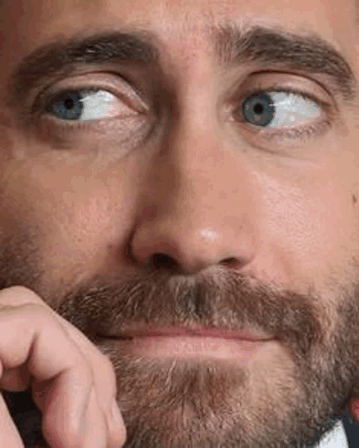 a man with a beard and blue eyes is making a funny face .