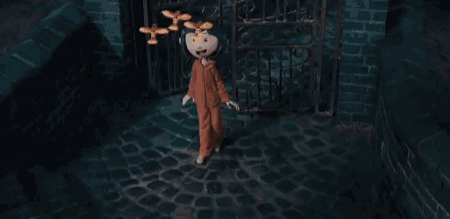a cartoon character from the movie coraline is standing in front of a gate in a dark room .
