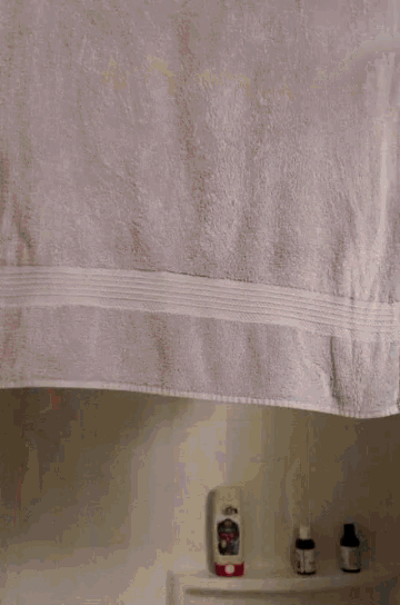 a white towel hangs from a shower curtain