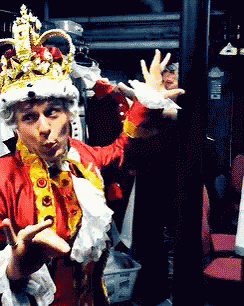 a man in a costume with a crown on his head is standing in a closet