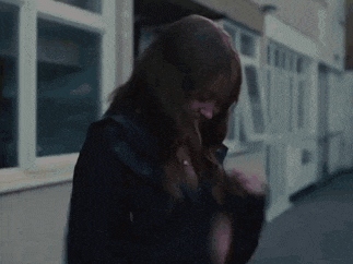 a woman with long red hair is walking down a street .
