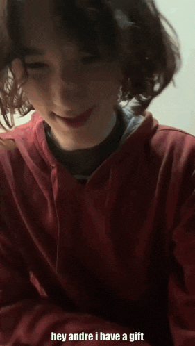 a young boy in a red hoodie is smiling and says hey andre i have a gift