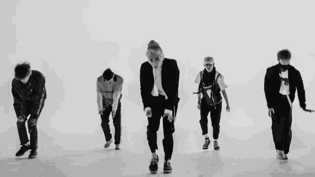 a group of young men are dancing in a line in a black and white photo .