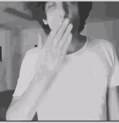 a man covering his mouth with his hand in a black and white photo .