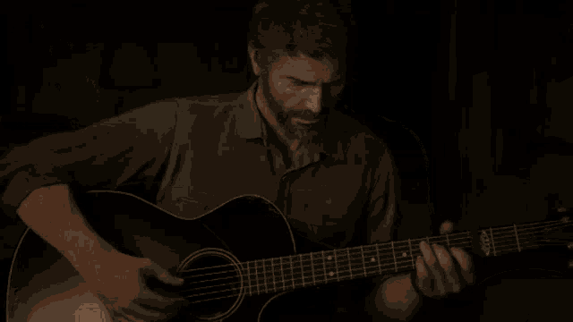 a man is playing an acoustic guitar in the dark .