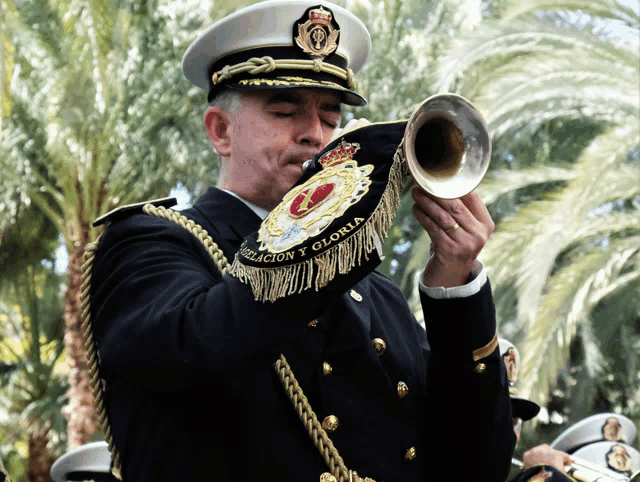 a man in a military uniform plays a trumpet with the word gloria embroidered on his uniform