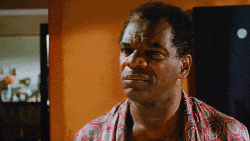 a man wearing a colorful shirt is looking at the camera