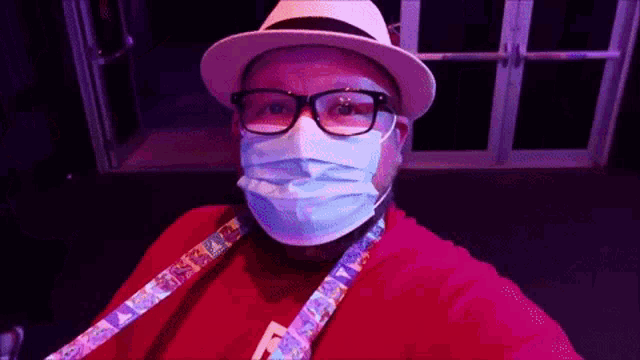 a man wearing a hat and a mask has a lanyard around his neck with the word disney on it