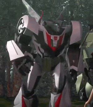 a transformer robot is standing in the grass in a forest .