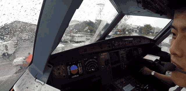 a man in a cockpit with a compass on the dashboard
