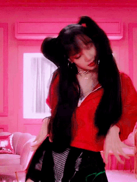 a woman in a red jacket is dancing in a room with pink walls