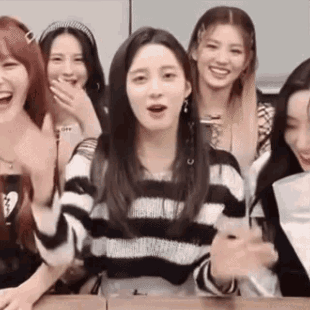 a group of young women are sitting around a table laughing and talking .