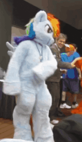 a person in a rainbow dash costume is standing in front of a group of people