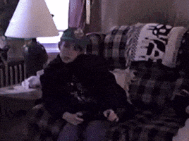 a person wearing a hat is sitting on a couch with a lamp