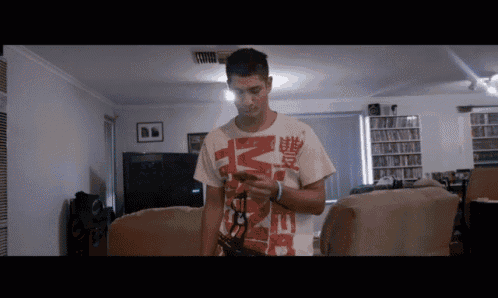 a man standing in a living room wearing a t-shirt that says mickey mouse on it