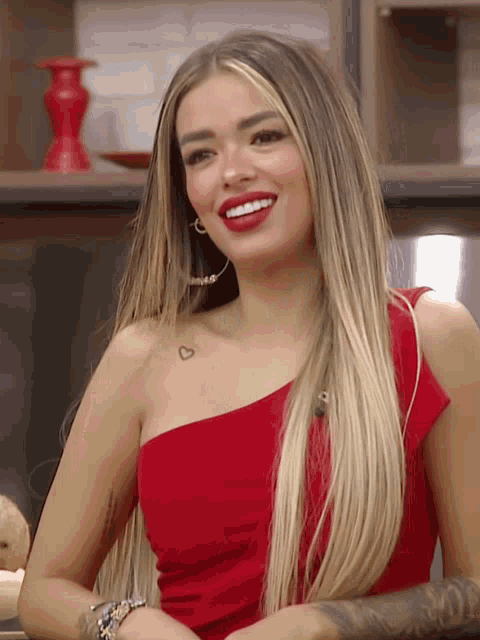 a woman in a red dress has a small heart tattoo on her chest