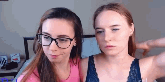two women wearing glasses and bras are standing next to each other .