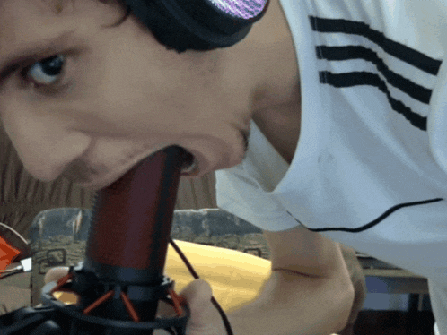 a man wearing headphones is biting into a microphone with his mouth