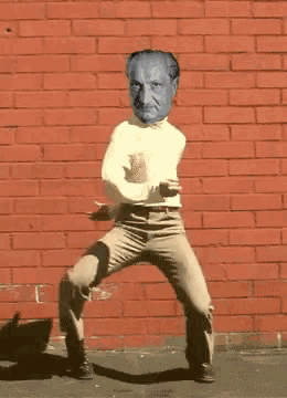 a man with a blue face is walking in front of a red brick wall