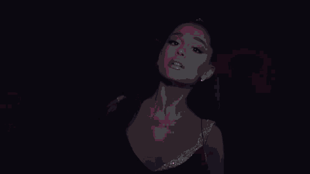 a woman in a black top is standing in front of a wall of pink lights