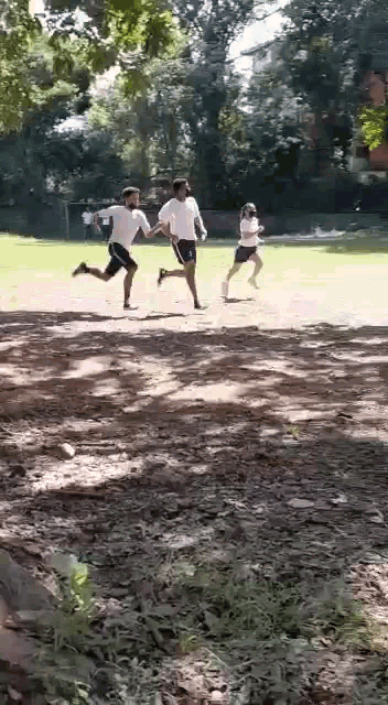 a group of men are running on a dirt field .