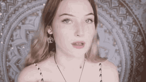 a woman wearing earrings and a necklace is looking at the camera .