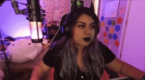 a woman wearing headphones and a cat ear headband is sitting in front of a microphone .