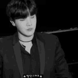 a black and white photo of a man wearing a suit and a choker