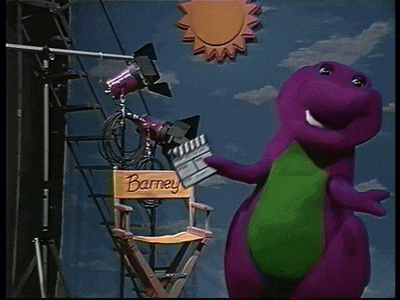 a purple dinosaur is standing next to a director 's chair with the name barney on it