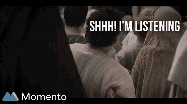 a shhh i 'm listening sign is above a crowd