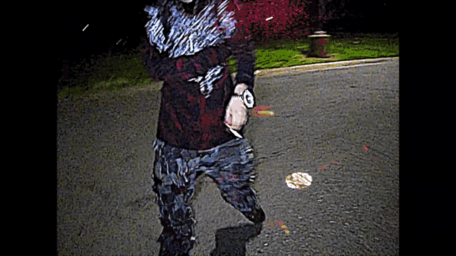 a person is walking down a street holding a knife .