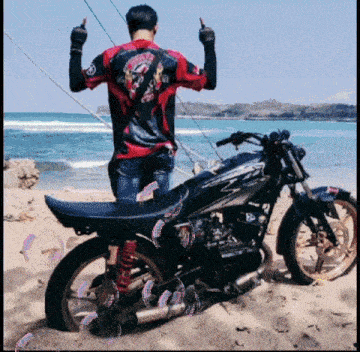 a man stands next to a motorcycle on the beach