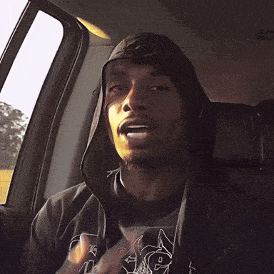 a man smoking a cigarette in a car while wearing a hat
