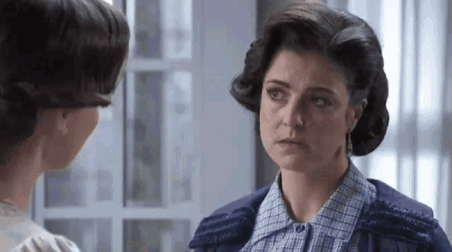 two women are standing next to each other in a room looking at each other .