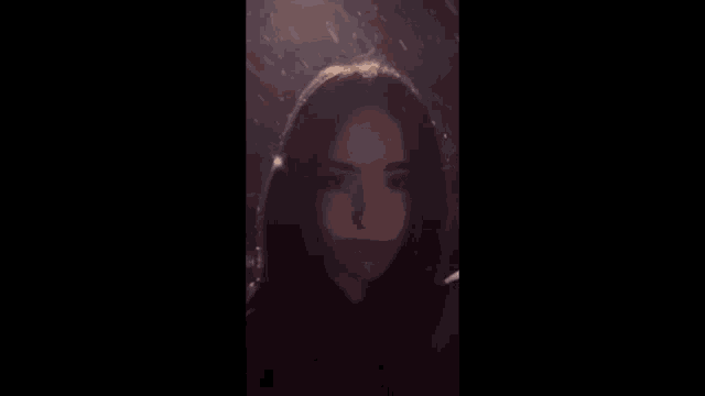 a woman is standing in the rain at night and looking at the camera .