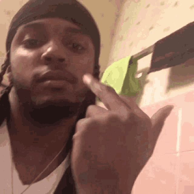 a man wearing a headband is giving the middle finger in a bathroom .