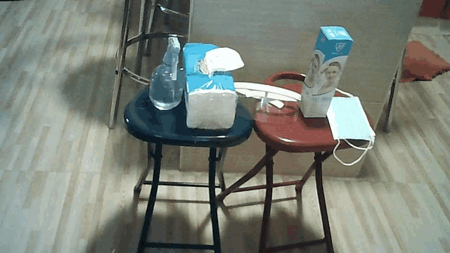 a box of face masks sits on a stool next to a tissue box
