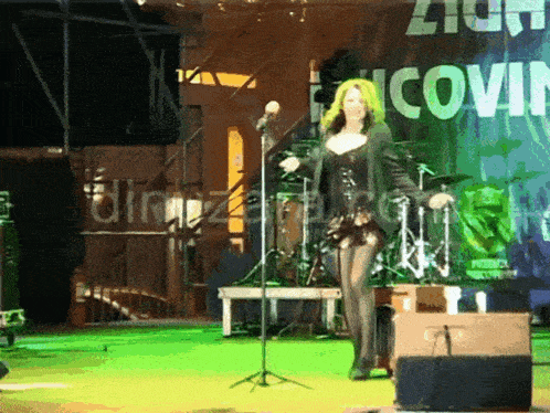 a woman singing into a microphone in front of a sign that says iconik