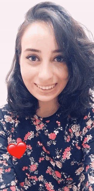 a woman wearing a floral shirt has a red heart on her shoulder