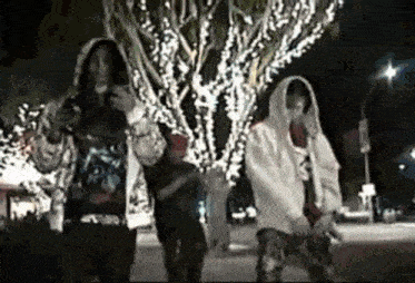 a group of people standing in front of a tree with christmas lights